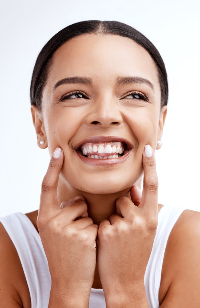 Confident woman showing bright smile with healthy teeth Close-up of a joyful woman pointing to her teeth with both hands, highlighting confidence and beauty