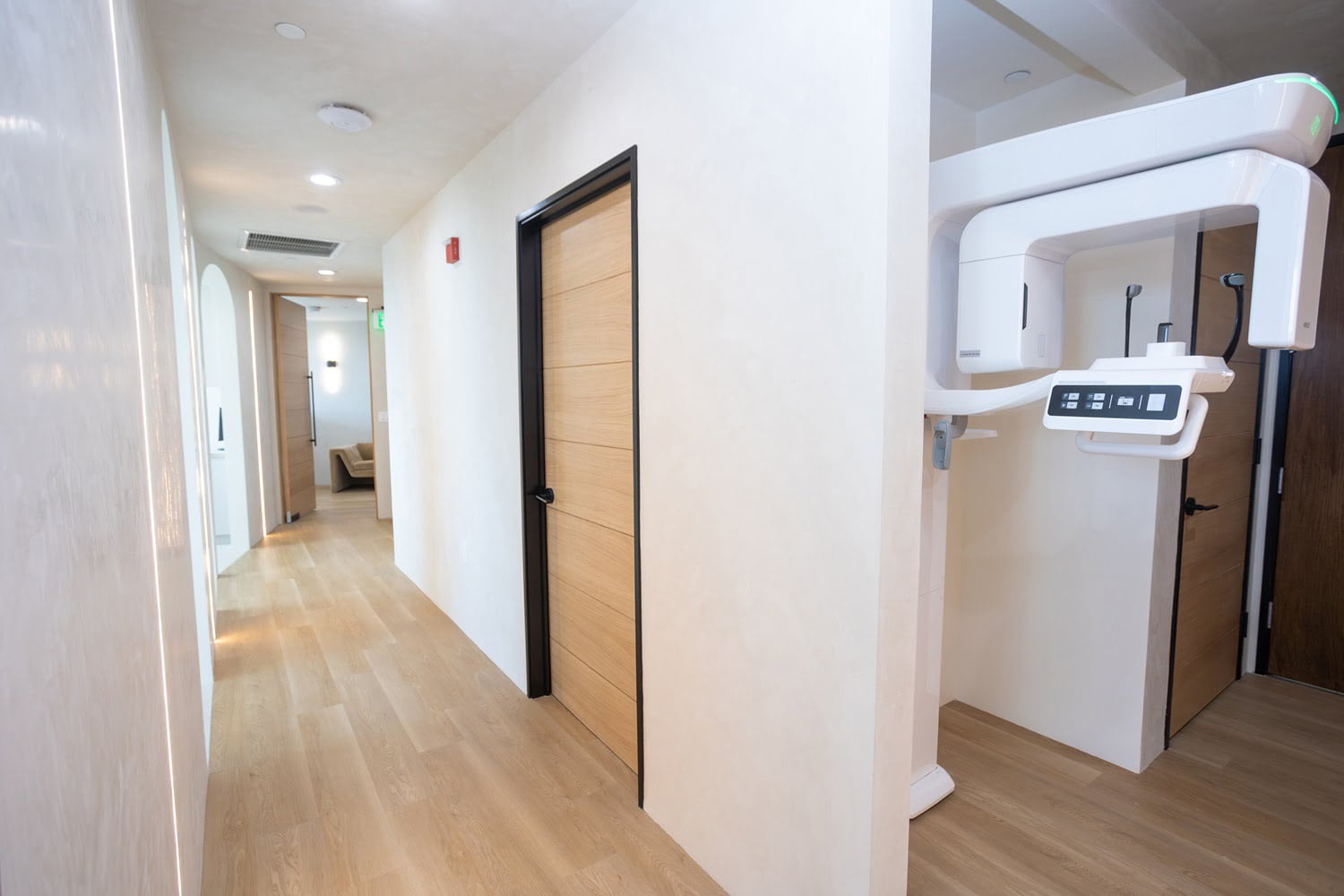 Bright hallway in a modern dental office with wood finishes and advanced panoramic X-ray machine, reflecting high-tech Invisalign care 