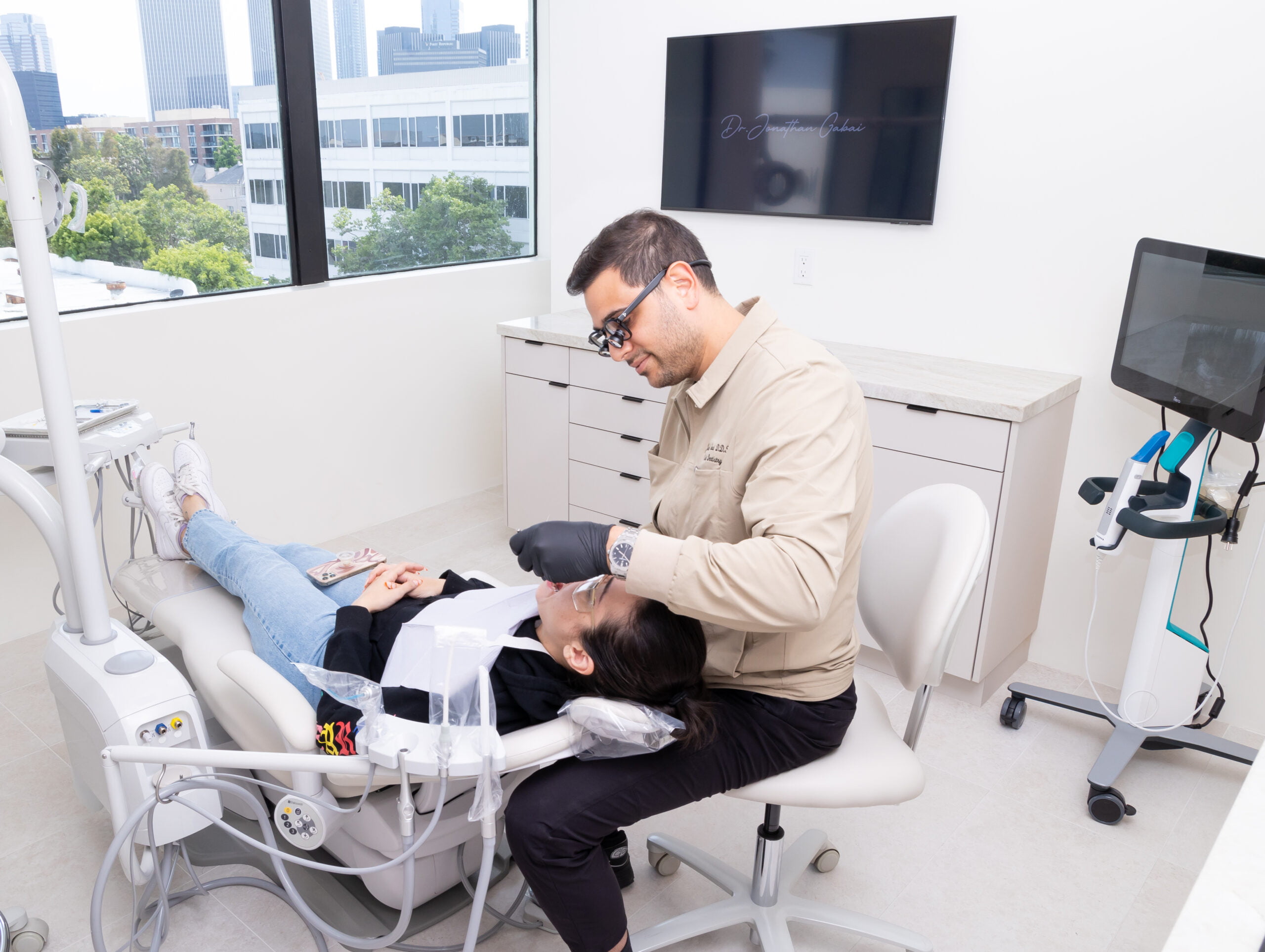 Dentist providing care to a patient in a modern clinic - Emergency Dental Care A dentist examines a patient in a bright, state-of-the-art dental office with advanced equipment and city views - Emergency Dental Care
