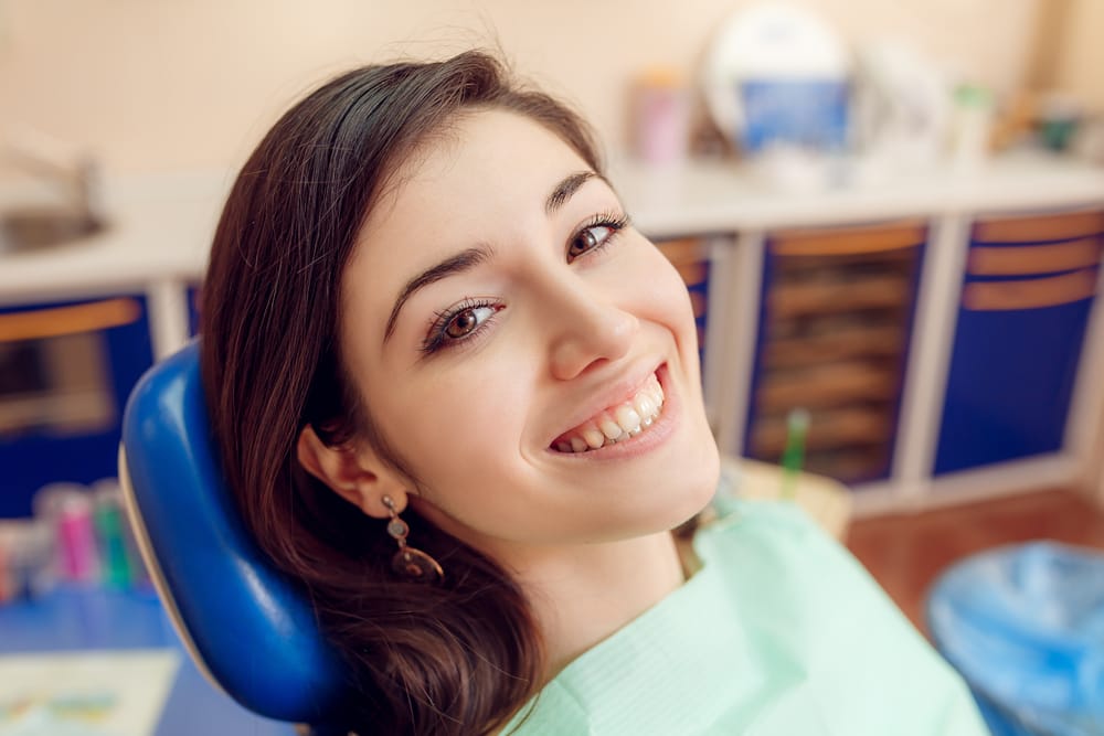 Young woman smiling in dental chair after porcelain veneer placement – Porcelain Veneers Los Angeles